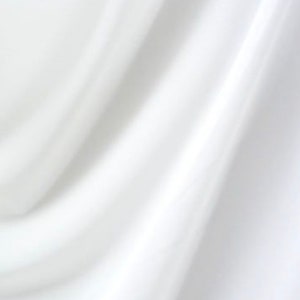 May include: White fabric with soft folds and wrinkles. The fabric is smooth and has a subtle sheen.