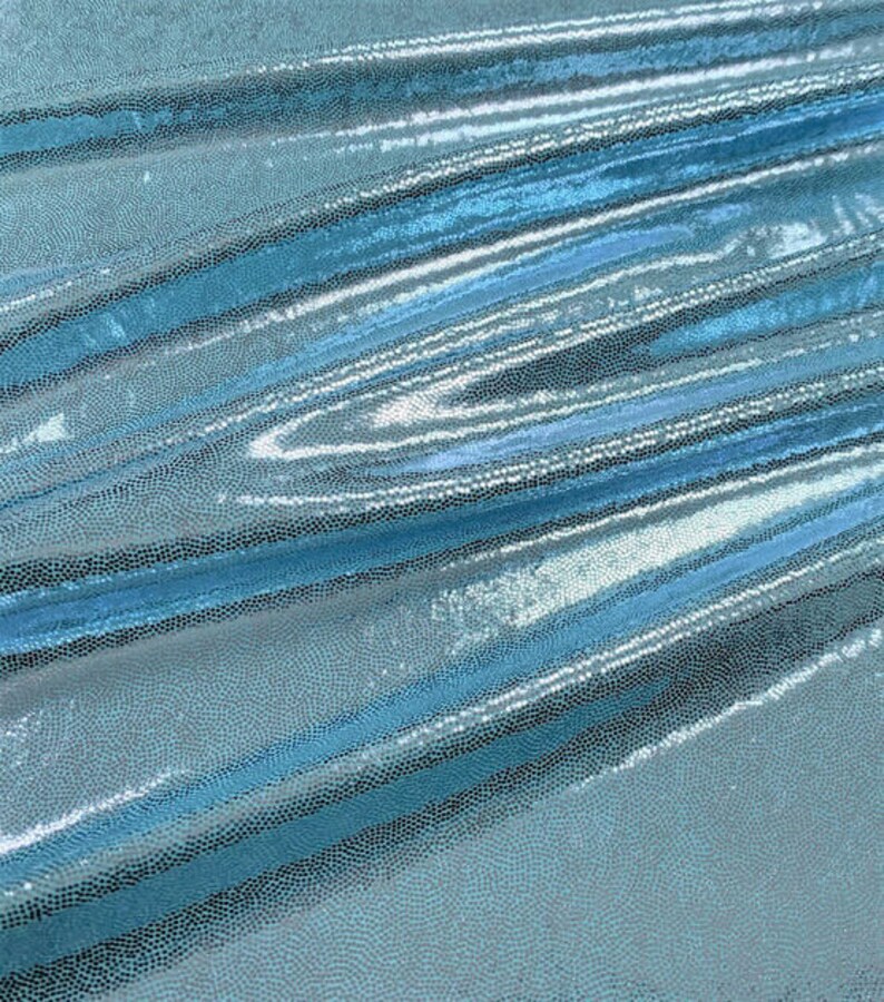 May include: A close-up of a light blue iridescent fabric with a textured, scaly pattern. The fabric is folded and draped, showing its shimmery and reflective surface.