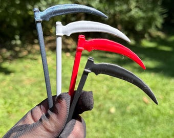 May include: Four miniature scythes held together, featuring long straight handles and curved blades. The scythes are colored in metallic dark gray, solid white, bright red, and matte black, each with a distinct curved blade and a vertical handle.