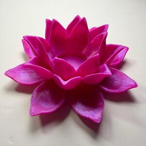 Puede incluir: Un portavelas con forma de flor de loto fucsia. La flor tiene m&uacute;ltiples p&eacute;talos con una superficie texturizada. El portavelas est&aacute; dise&ntilde;ado para sostener una peque&ntilde;a vela en el centro, creando un ambiente hermoso y sereno.