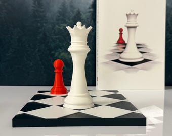 May include: A white chess queen piece and a small red pawn standing on a black and white checkered board. Behind the board is a book cover featuring an illustration of a white queen and a red pawn on a checkered surface against a forest backdrop.