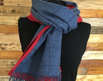 May include: A blue and red scarf with a checkered pattern and fringe. The scarf is folded and displayed on a mannequin.
