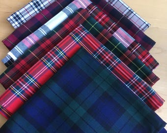May include: A set of seven plaid fabric squares in various colors, including red, blue, green, white, and black. The squares are arranged in a stack, with the largest square at the bottom and the smallest square at the top.