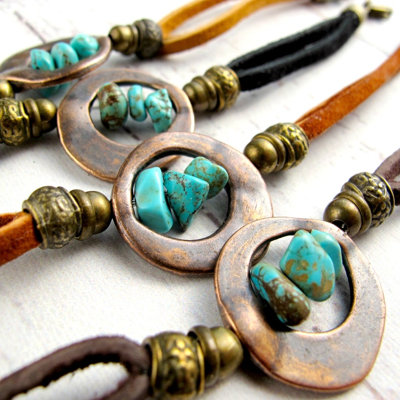May include: Four leather cord necklaces with copper circle pendants and turquoise stones. Each necklace has a different color cord: brown, black, tan, and brown.