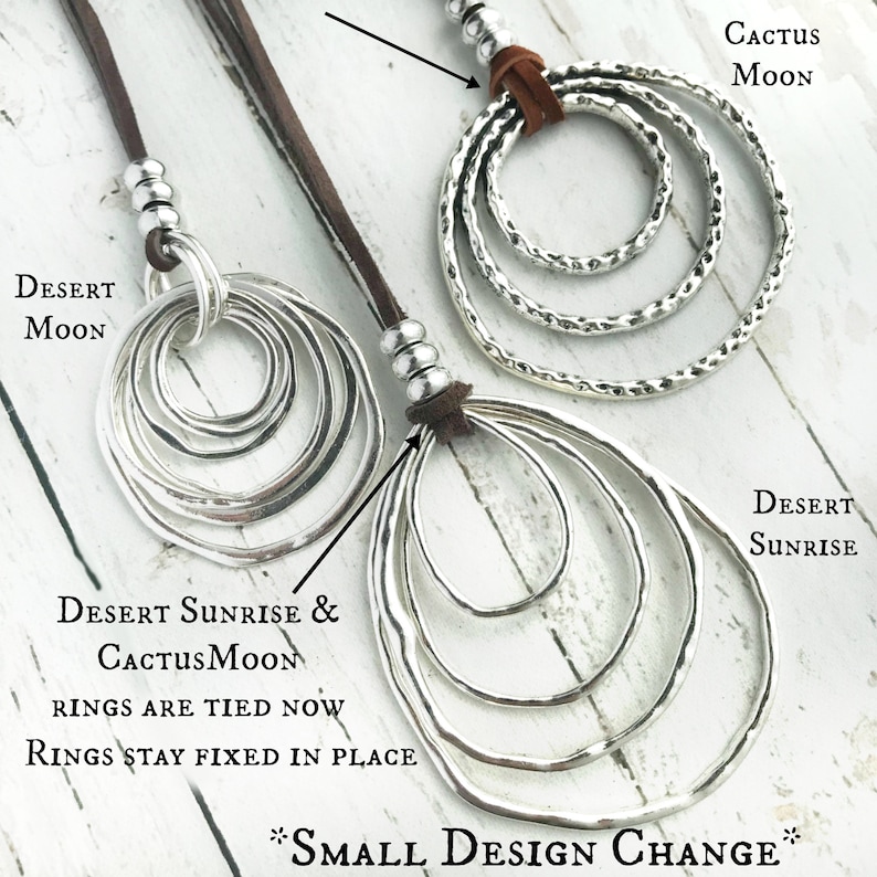 May include: Two silver circle pendant necklaces with brown leather cords. The necklaces feature multiple circles of varying sizes. The text "DESERT SUNRISE & CACTUSMOON RINGS ARE TIED NOW RINGS STAY FIXED IN PLACE *SMALL DESIGN CHANGE*" is visible below the necklaces.