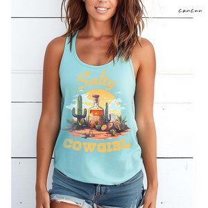 K&ouml;nnte beinhalten: Hellblaues Tanktop mit W&uuml;stenmotiv. Das Design zeigt eine Flasche, Kakteen und die gelben Worte "Salty Cowgirl". Das Tanktop ist &auml;rmellos und hat ein Racerback-Design.
