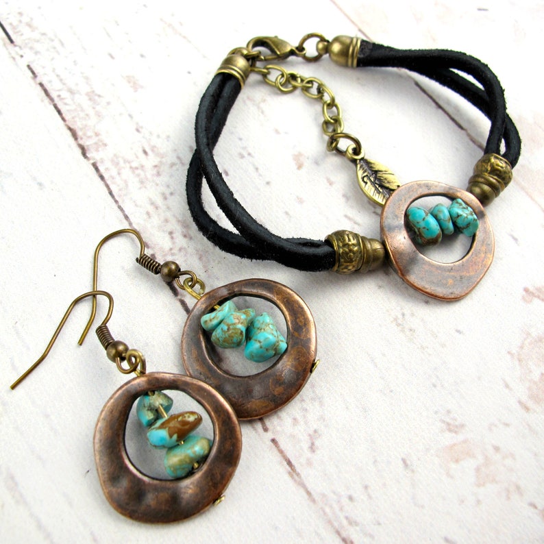 May include: A set of turquoise and copper jewelry featuring a leather bracelet with a copper circle pendant and a pair of earrings with copper circles and turquoise stones.