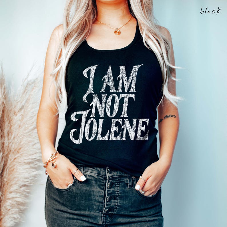 Pu&ograve; includere: Canotta nera con la scritta "I AM NOT JOLENE" in un carattere bianco invecchiato. Il top &egrave; uno stile halter e viene indossato con jeans scuri. La parola "black" &egrave; scritta in alto a destra.