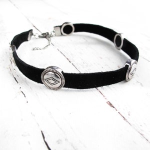 May include: Black suede choker necklace with silver-toned metal accents. The accents feature a geometric diamond shape.