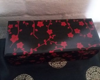 May include: Black rectangular box with a red floral design. The box has a glossy finish.
