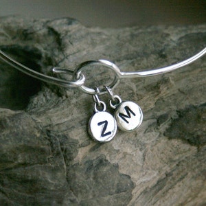 May include: Silver bangle bracelet with two charms, one with the letter "Z" and the other with the letter "M".