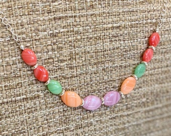 May include: A silver chain necklace with oval-shaped beads in shades of pink, orange, and green.