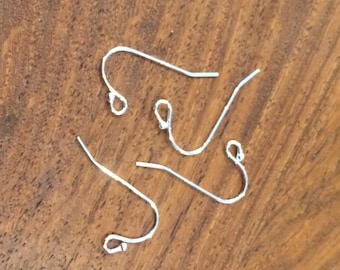 May include: Three silver earring hooks, each with a small loop at the top and a curved hook at the bottom.