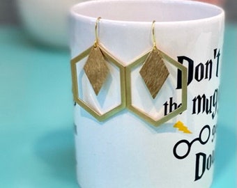 May include: Gold hexagon earrings with a diamond-shaped cutout and a gold-toned finish.