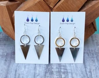 May include: Two pairs of earrings displayed on white cards. The earrings are silver and gold with a triangle shape and a circle. The cards have the text "Zoom Pop Design" printed on them.