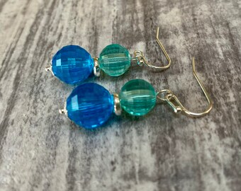 May include: A pair of dangle earrings with two blue and green glass beads on each earring. The earrings have silver hooks.