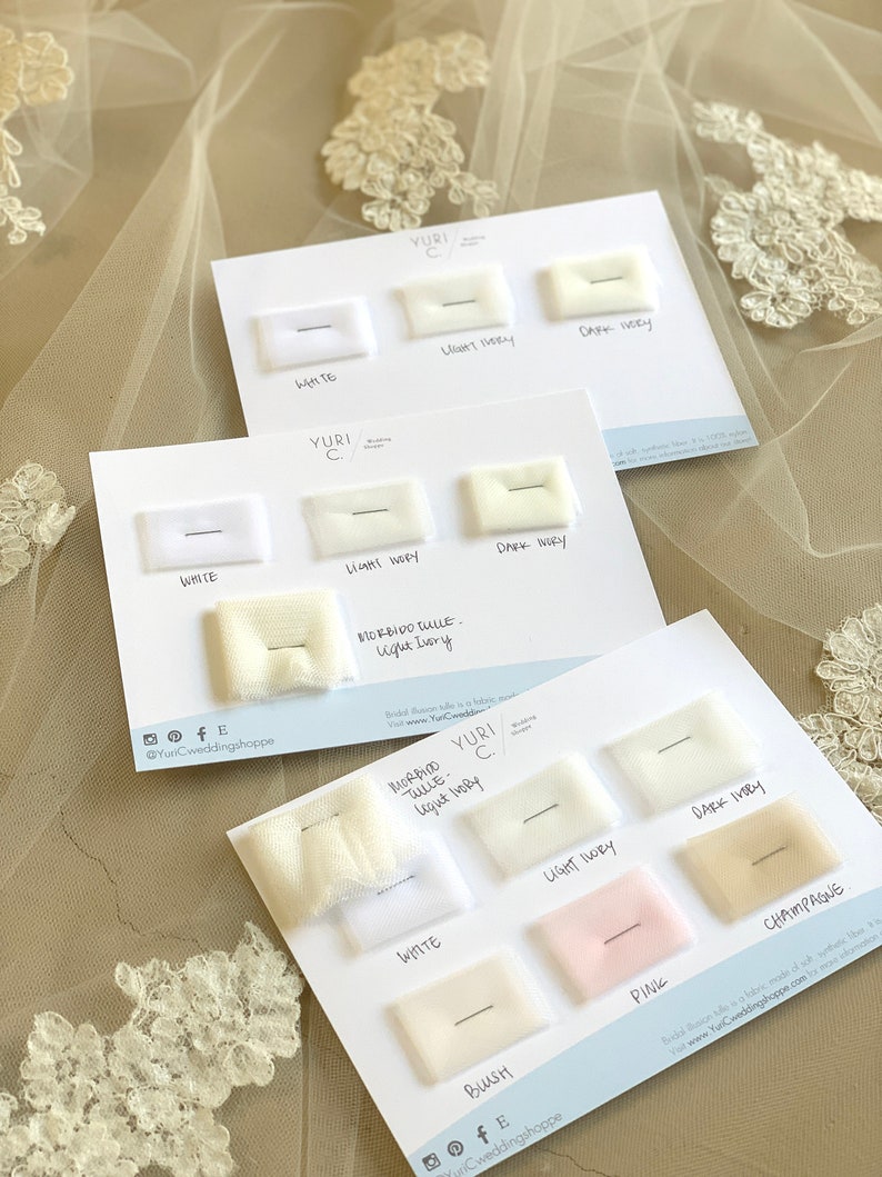 May include: A white card with swatches of different colored tulle fabric. The swatches are labeled with the color names: White, Light Ivory, Dark Ivory, Champagne, Blush, and Pink. The card also includes the text "Yuri C." and "Morbido Tulle - Light Ivory".