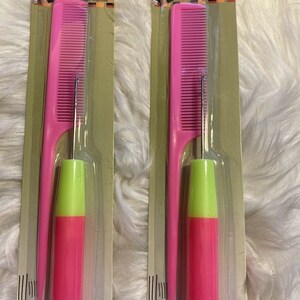 May include: Two pink crochet needle and comb sets. Each set includes a pink comb and a pink crochet needle with a green tip. The packaging is labeled "Crochet Needle & Comb Set" and "Ensemble Aiguille a Crochet et Peigne".