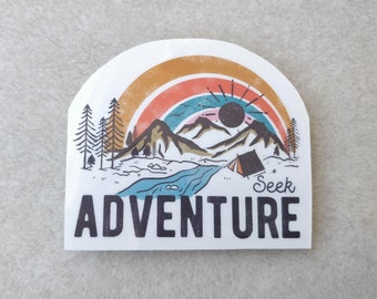 May include: White sticker with a retro-style illustration of a mountain landscape, rainbow, and sun. The sticker has the words "Seek Adventure" in a bold font. The design includes trees, a river, and a tent.