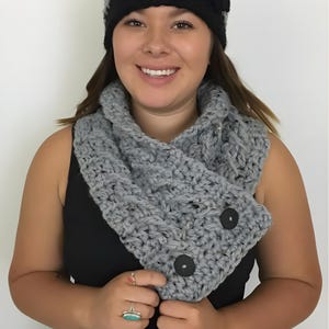 Elegant crochet cable button scarf made with super bulky yarn for warmth and rich texture. Features classic cable stitches and decorative buttons for a cozy, stylish finish. Shown in soft neutral tones, perfect for layering during fall and winter. Quick and easy PDF crochet pattern for beginners and advanced makers. A beautiful handmade cowl or neck warmer ideal for gifts, markets, or personal winter wear.
