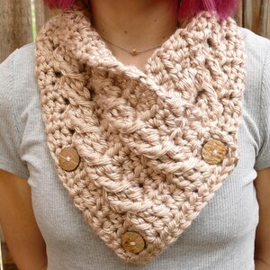 Elegant crochet cable button scarf made with super bulky yarn for warmth and rich texture. Features classic cable stitches and decorative buttons for a cozy, stylish finish. Shown in soft neutral tones, perfect for layering during fall and winter. Quick and easy PDF crochet pattern for beginners and advanced makers. A beautiful handmade cowl or neck warmer ideal for gifts, markets, or personal winter wear.