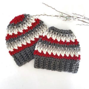 Peut inclure: Deux bonnets en crochet &agrave; rayures rouges, blanches et grises. Les bonnets sont faits avec un fil &eacute;pais et ont un style simple et ample.