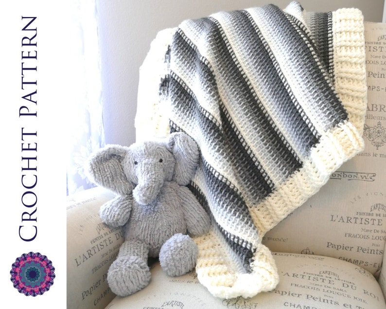 May include: A crocheted baby blanket with white and gray stripes. The blanket is draped over a chair with a gray stuffed elephant toy sitting on the chair.