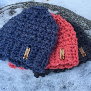 Peut inclure: Trois bonnets en crochet de diff&eacute;rentes couleurs&nbsp;: bleu, corail et gris. Chaque bonnet est dot&eacute; d&rsquo;une petite &eacute;tiquette en bois sur laquelle est inscrit le texte &laquo;&nbsp;Made with Love&nbsp;&raquo;.