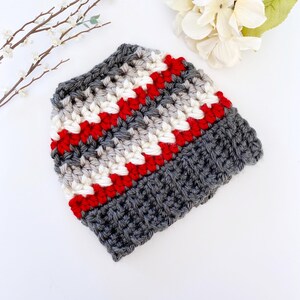 Peut inclure: Un bonnet en crochet ray&eacute; gris, blanc et rouge.