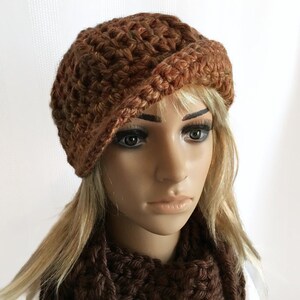 May include: A brown crocheted hat with a folded brim. The hat is made of a textured yarn in shades of brown and tan. The hat is part of a set that includes a matching scarf. The hat is a stylish accessory.