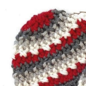 Peut inclure: Gros plan sur un chapeau crochet&eacute; avec des rayures rouges, blanches et grises.