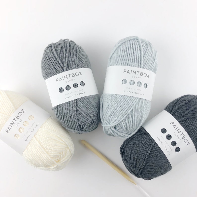May include: Four balls of yarn in different shades of gray, white, and light blue. The yarn is labeled "Paintbox Yarns Simply Chunky".