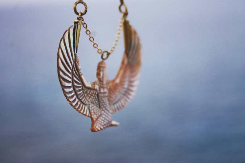 May include: A gold chain necklace with a detailed, carved, white and brown winged figure pendant.