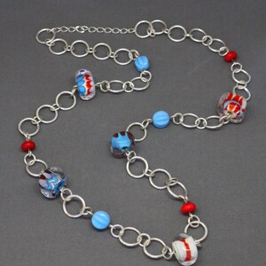 May include: A silver chain necklace with colorful glass beads. The beads are red, blue, and white with swirling patterns.