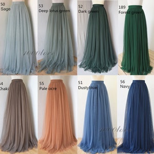 May include: Eight tulle skirts in different colors, including sage, deep lotus green, dark green, forest green, khaki, pale ochre, dusty blue, and navy. The skirts are all full-length and have a high waist.