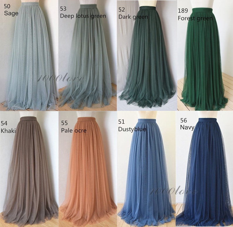 May include: Eight tulle skirts in different colors, including sage, deep lotus green, dark green, forest green, khaki, pale ochre, dusty blue, and navy. The skirts are all full-length and have a high waist.