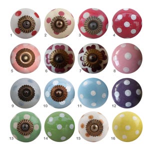 Peut inclure: Seize boutons de placard en céramique colorés avec divers motifs à pois. Les boutons présentent une variété de couleurs, dont le rouge, le rose, le bleu, le vert et le jaune. Chaque bouton a une base en métal et est numéroté de 1 à 16.