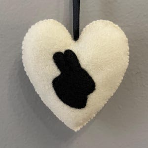 May include: White felt heart-shaped ornament with a black felt bunny silhouette.