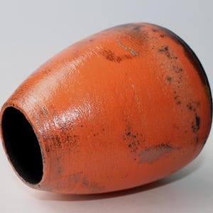 May include: Orange ceramic vase with black speckles and a glossy finish.