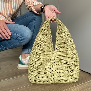 May include: A light green crocheted tote bag with a wide, open top and a single handle.