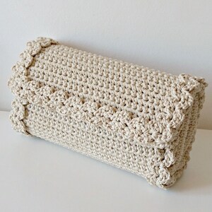 May include: A beige crocheted clutch bag with a scalloped edge.