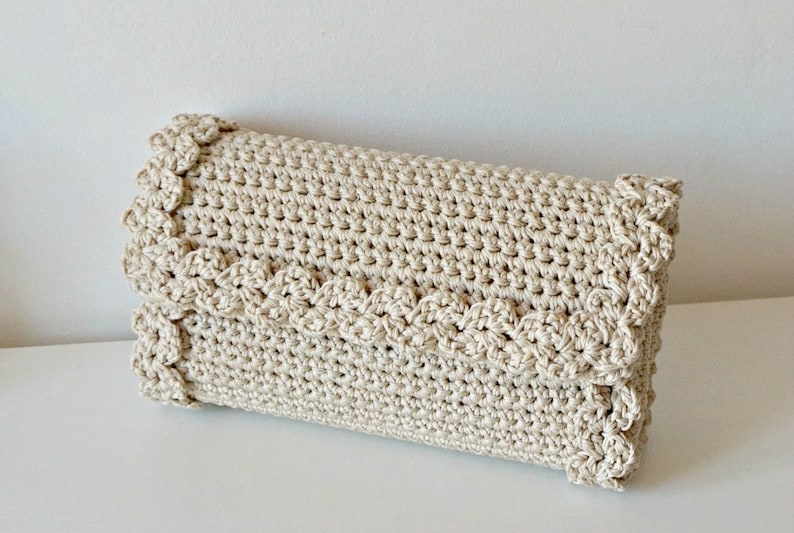 May include: A beige crocheted clutch bag with a scalloped edge.