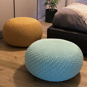 May include: Two round knitted ottomans, one mustard yellow and one light blue, on a wooden floor.