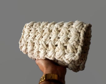 May include: A cream-colored crocheted clutch bag with a textured design.
