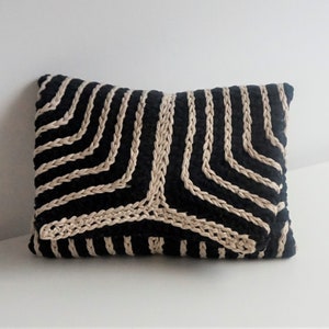 Puede incluir: Almohada rayada en negro y beige con un patr&oacute;n geom&eacute;trico. La almohada est&aacute; hecha de un tejido tejido y tiene una forma rectangular.