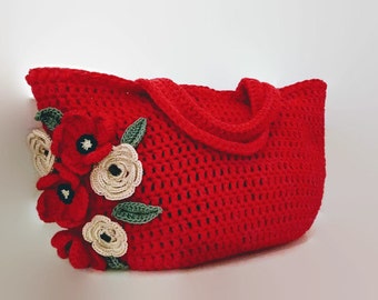 May include: Red crocheted tote bag with a floral design. The flowers are crocheted in white and red.