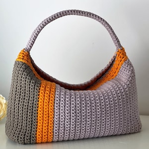 May include: A crocheted handbag with a single handle. The bag is made with three colors of yarn: gray, orange, and light purple.