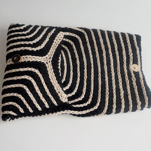 Puede incluir: Clutch de crochet a rayas negras y crema con cierres de presi&oacute;n dorados.