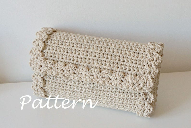 May include: A crocheted clutch bag with a scalloped edge in a cream color. The bag is made with a simple stitch pattern and has a soft, textured look.
