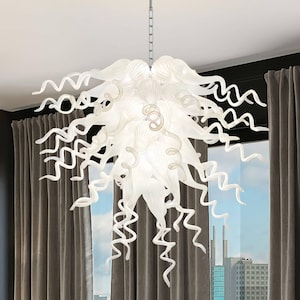 May include: A white glass chandelier featuring numerous elongated, spiraling, and ribbon-like glass elements that extend outward from a central point. The fixture is suspended by a thin metal chain and emits a soft, diffused light throughout.